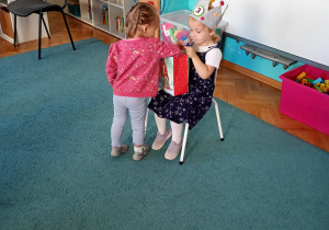 Telimena częstuje dzieic słodkościami. Dziewczynka w różowej bluzie składa życzenia.