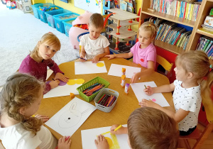 Dzieci z żółtego stolika wykonują pracę plastyczną