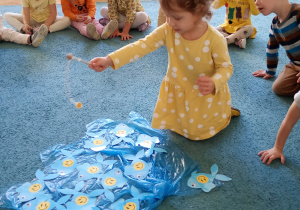 ę. Łowi rybki z uśmiechem rozłożone na niebskiem dywanie