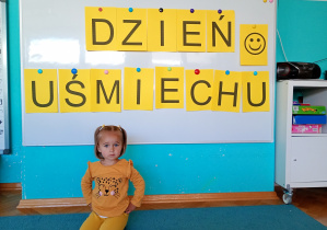 Chłopiec w żółtej koszulce łowi rybki rozłożone na niebsiekim dywanie.