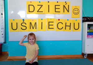 Dziewczyna w bluzce w żółtk białe paski tlepisu dzień uśmeichu przywieszonego na białej tablicy