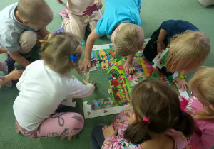 Dzieci wspólnie układają puzzle na dywanie