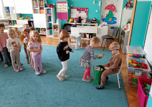 Solenizant siedzi na krześle. Dzici stopją w kolejce, aby złożyć mu zyczenia. Mark rozdaje każdemu dziecku po kolei przygotowane upominki