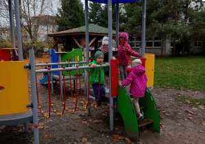 Przedszkolaki pozują do zdjęcia, za nimi znajduje się piaskownica.