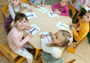 Dzieci wyklejają szablon litery T plasteliną