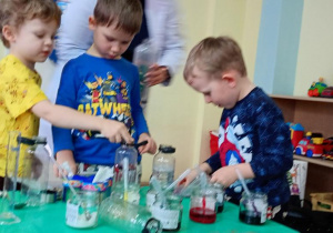 Tymek, Staś i Olek wykonują zaczarowane butelki.