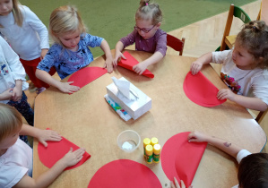 Dzieci zginają czerwone koło na pół, aby stworzyć kapelusz muchomora