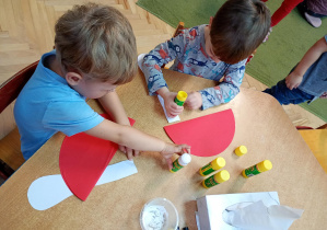 Chłopcy tworzą muchomory z papieru