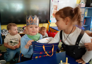 Dziewczynka częstuje się urodzinowym cukierkiem od kolegi