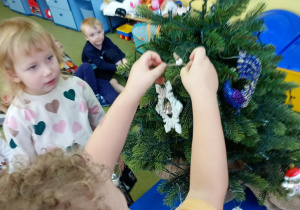 Chłopiec zawiesza gwiazdkę na przedszkolnej choince