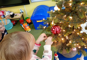 Dziewczynka zawiesza na choince ozdobę