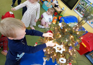 Chłopiec zawiesza na choince bombkę