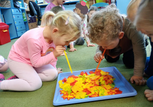 Dziewczynka i chłopiec zdmuchują liście z ilustracji jeża