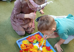 Dziewczynka i chłopiec zdmuchują liście z ilustracji jeża