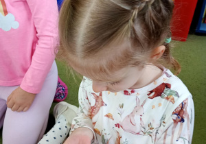 Dziewczynka przygląda się makaronikowi, który prezentuje w powiększeniu kolec jeża