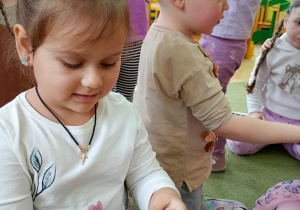 Dziewczynka bada, w jaki sposób kłuje szyszka