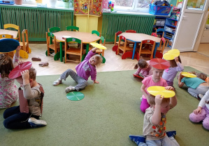 Dzieci chowają się pod kolorowymi krążkami niczym jeżyki pod liśćmi