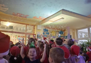 Dzieci chwytają wirujące w powietrzu mydlane bańki