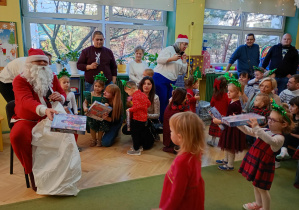 Święty Mikołaj rozdaje dzieciom prezenty