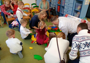 Dzieci z rodzicami bawią się wspólnie otrzymanymi prezentami od Mikołaja