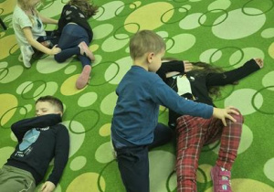 dzieci ćwiczą między sobą pozycję bezpieczną