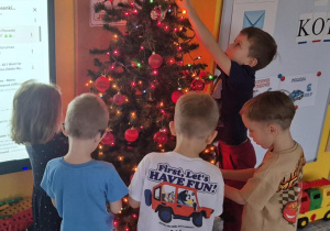 dzieci ubierają wspólnie choinkę
