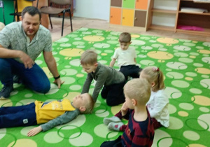 ratownik pokazuje na Julku jak udzielić pomocy osobie nieprzytomnej