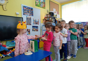 Dziewczynka częstuje się urodzinowym cukierkiem od koleżanki