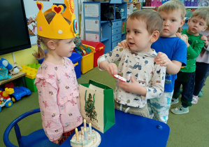 Chłopczyk częstuje się urodzinowym cukierkiem od dziewczynki