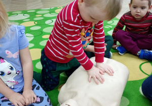 Chłopiec uczy się wykonywać masaż serca na fantomie