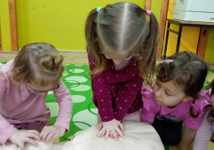 Dziewczynka uczy się wykonywać masaż serca na fantomie