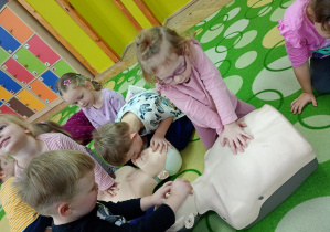 Dziewczynka uczy się wykonywać masaż serca na fantomie