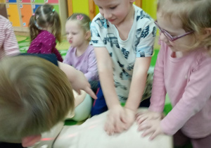 Chłopiec uczy się wykonywać masaż serca na fantomie