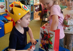 Dziewczynka częstuje się urodzinowym cukierkiem od kolegi