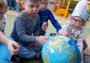 Maluszki oglądają globus, przyglądając się miejscom życia ryb