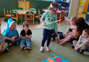 Dziewczynka łowi na wędkę papierową sylwetę ryby