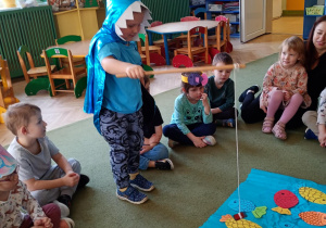 Chłopiec łowi na wędkę papierową sylwetę ryby