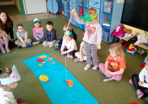 Dziewczynka łowi na wędkę papierową sylwetę ryby