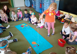 Dziewczynka łowi na wędkę papierową sylwetę ryby