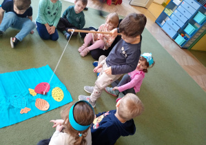 Chłopiec łowi na wędkę papierową sylwetę ryby