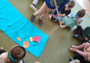 Chłopiec łowi na wędkę papierową sylwetę ryby