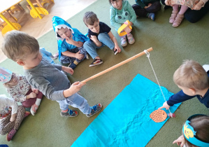 Chłopiec łowi na wędkę papierową sylwetę ryby