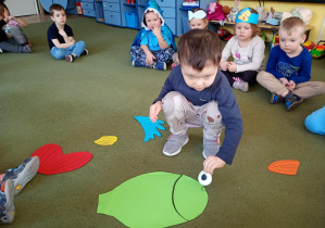 Chłopiec składa z części sylwetę ryby