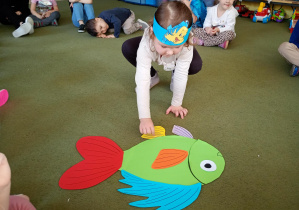 Dziewczynka składa z części sylwetę ryby