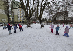 Dzieci trenują rzuty śnieżkami celując w drzewa