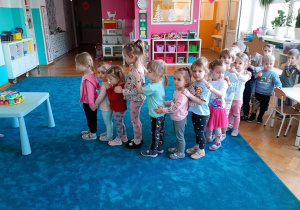 Dzieci stoją w pociągu na niebieskim dywanie. Czekają na złożenie zuczen dla solenizantki.