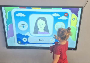 Oliwia gra na tablicy multimedialnej