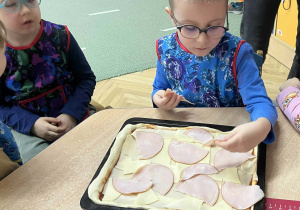 Układanie składników na pizzy