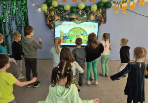 Dzieci tańczą naśladując postaci na tablicy multimedialnej