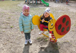 Dziewczynki bawią się na bujaku biedronce